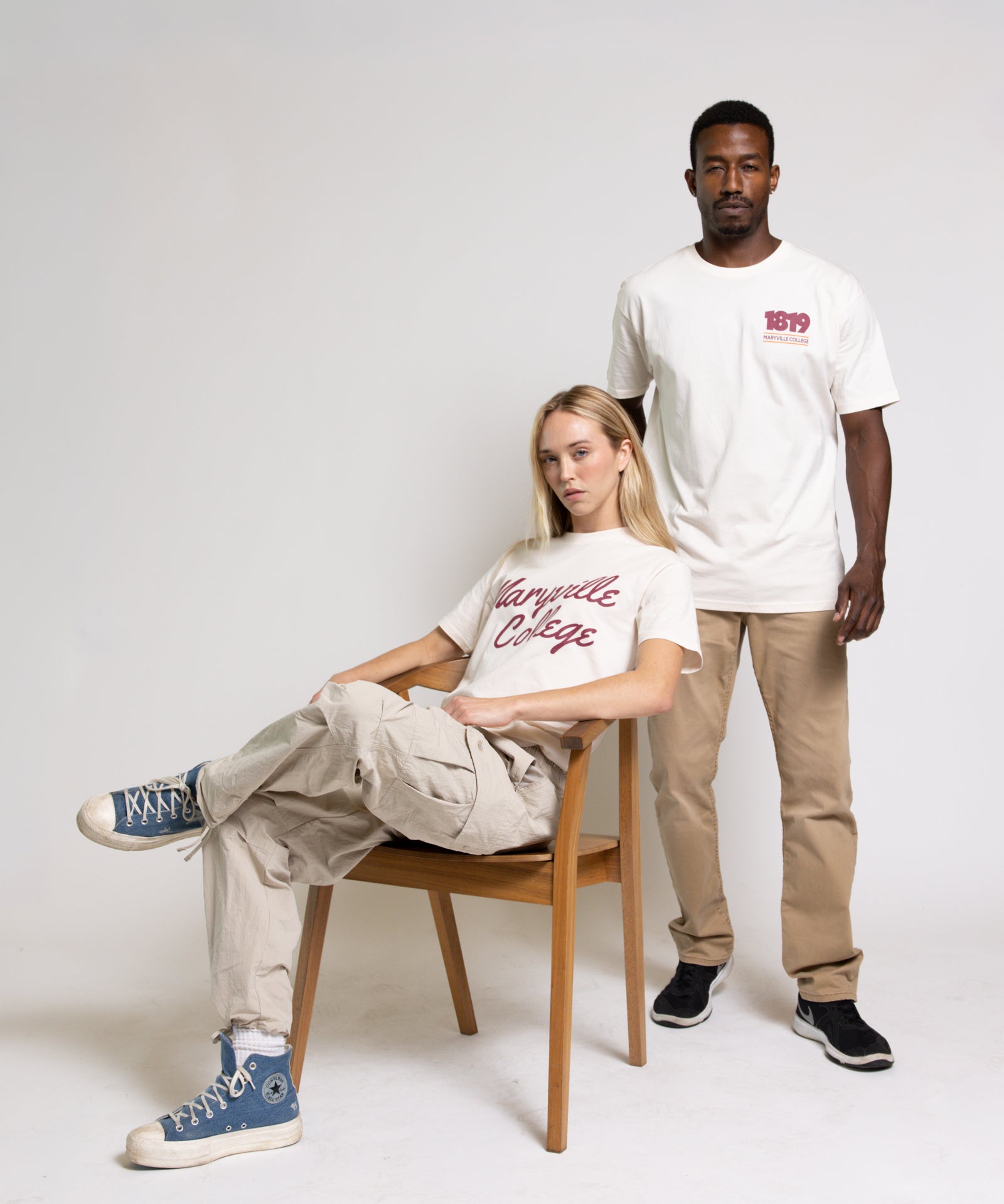 Two people wearing cream t-shirts with red text on a white background